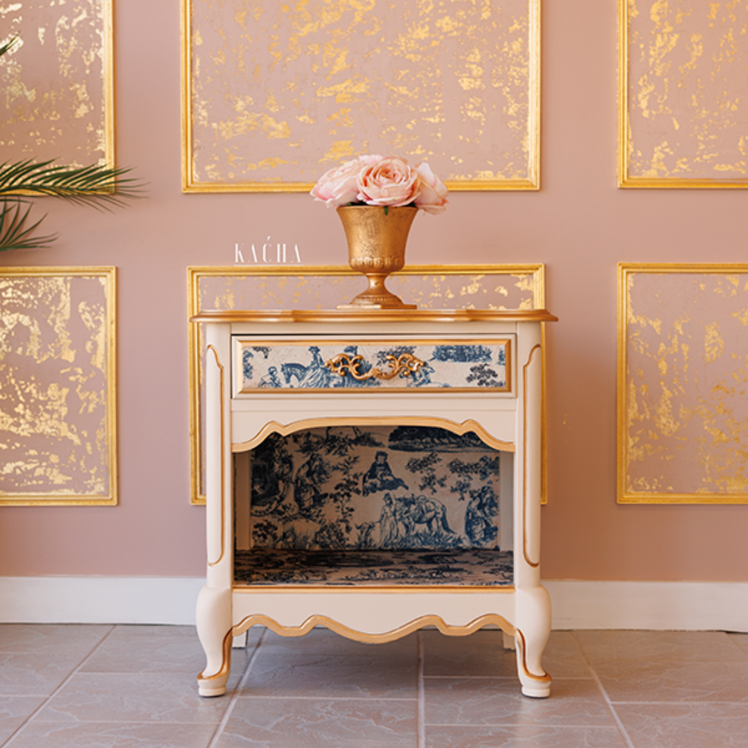 Decorative cabinet with floral design in a room with gold-framed artwork on the wall.