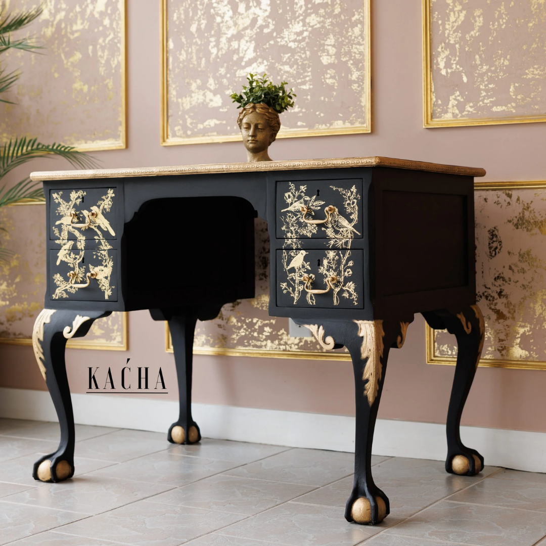 Decorative black desk with gold accents in a room with framed artwork on the wall.