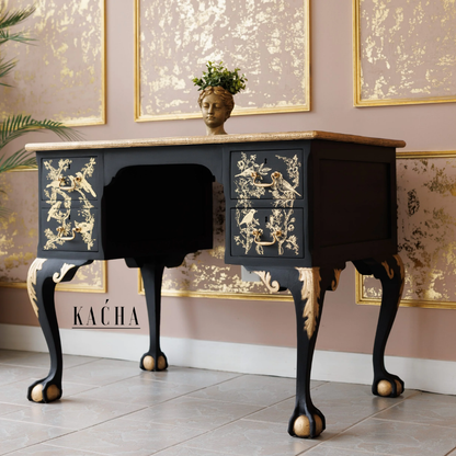 Decorative black desk with gold accents in a room with framed artwork on the wall.