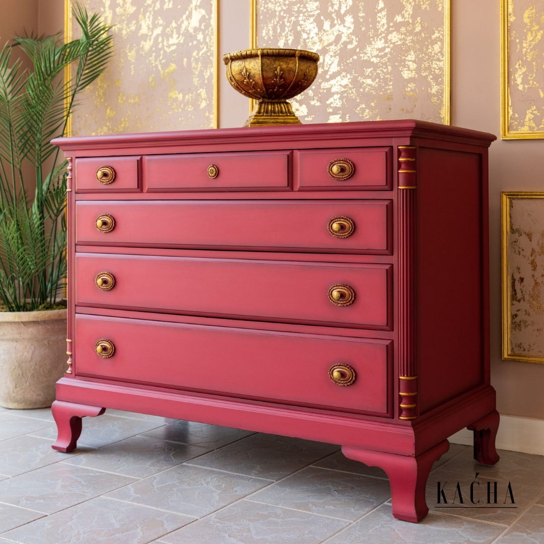 Red dresser with gold accents in a room with decorative elements