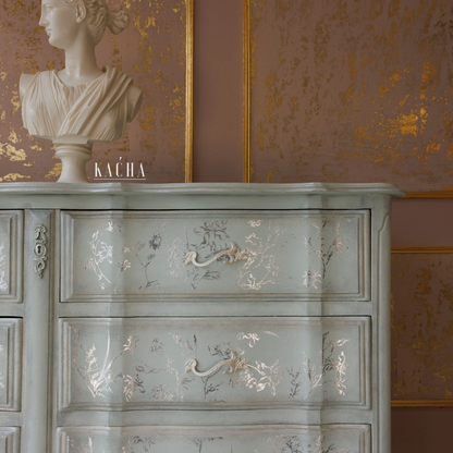 Decorative cabinet with floral patterns against a wall with gold leaf design